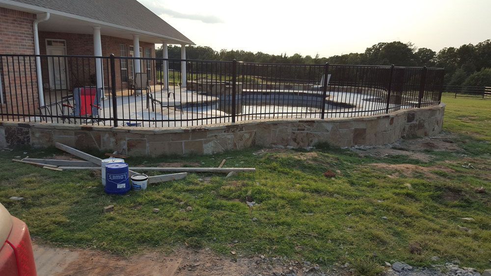 A fence around a pool is being built in front of a house