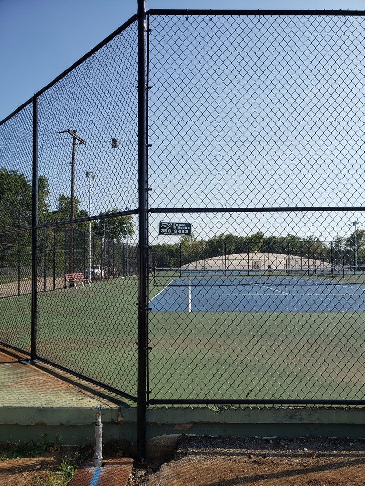 A tennis court is behind a chain link fence