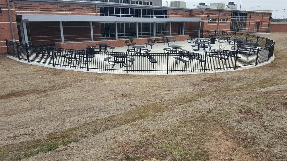 A fenced with tables and chairs in front of a building