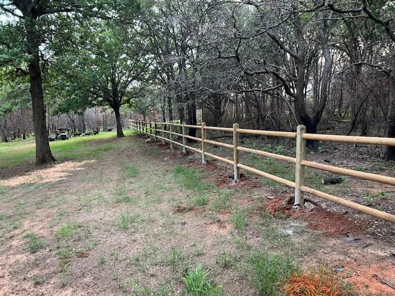 A wooden fence is surrounded by trees in a field