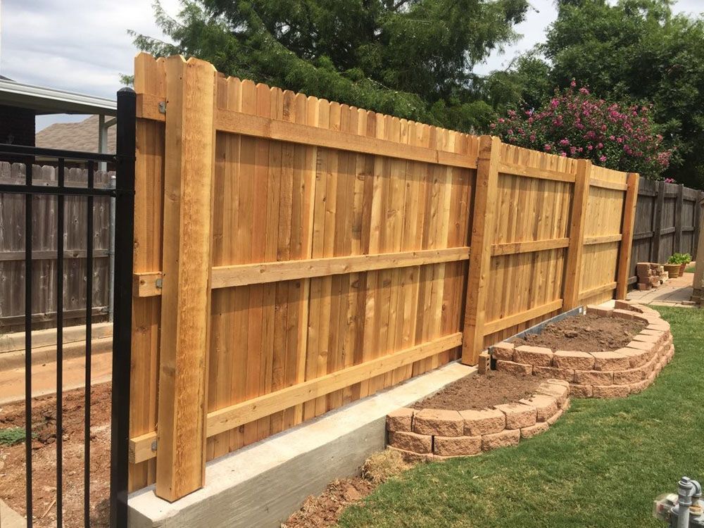 A wooden fence with a black gate in a backyard
