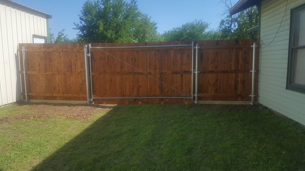 A wooden fence with a gate in the backyard of a house