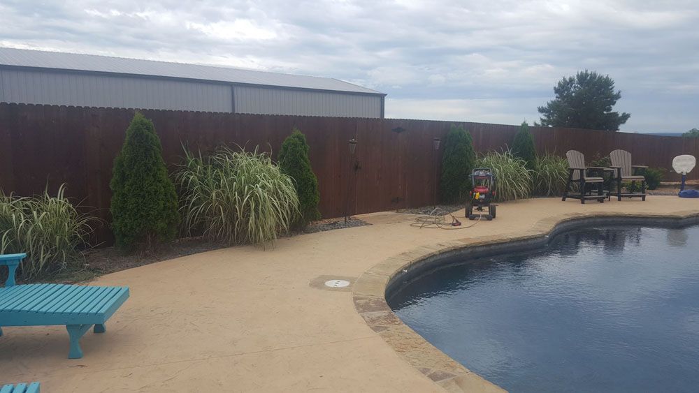 There is a swimming pool in the backyard with a wooden fence surrounding it
