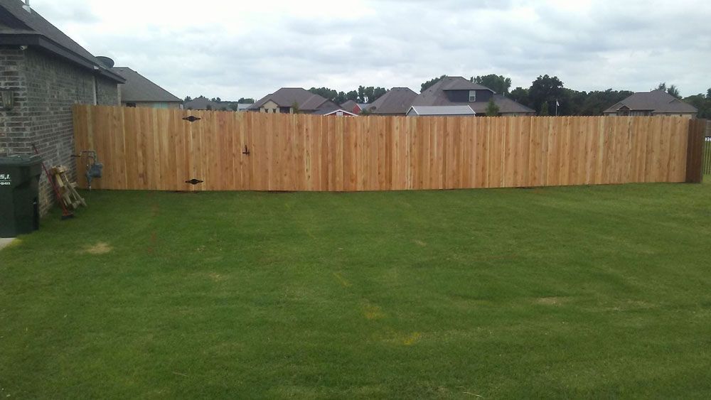 A wooden fence surrounds a lush green lawn in a backyard