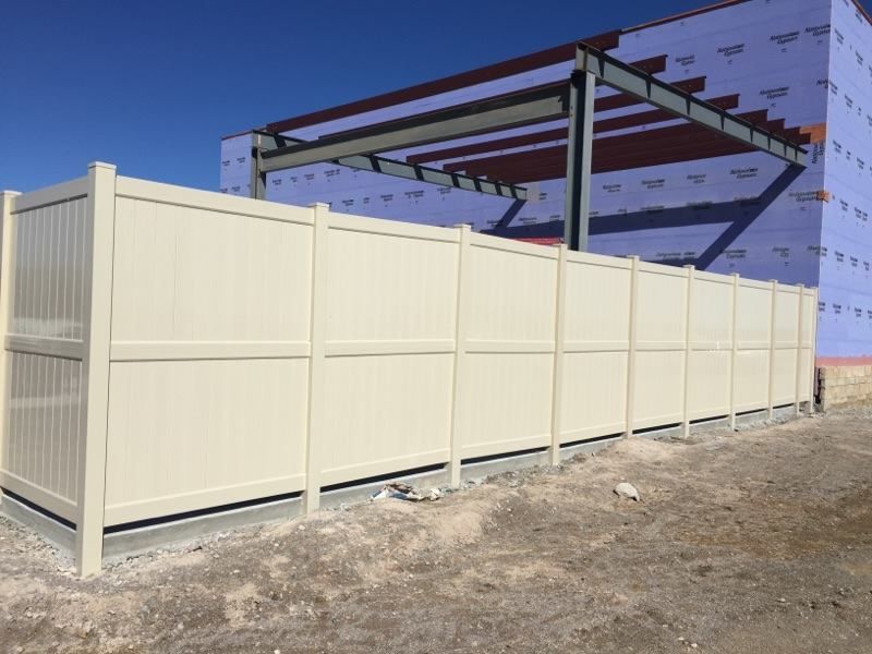 A white fence is in front of a building under construction