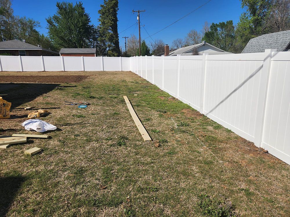 A white fence is in the middle of a grassy yard