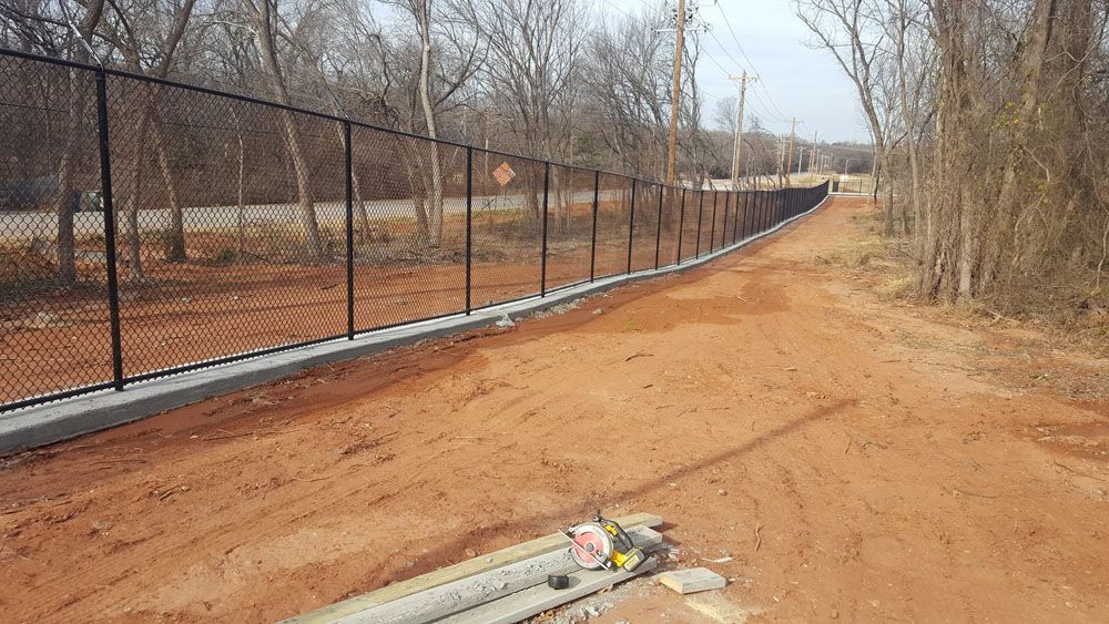 A chain link fence is along the side of a dirt road