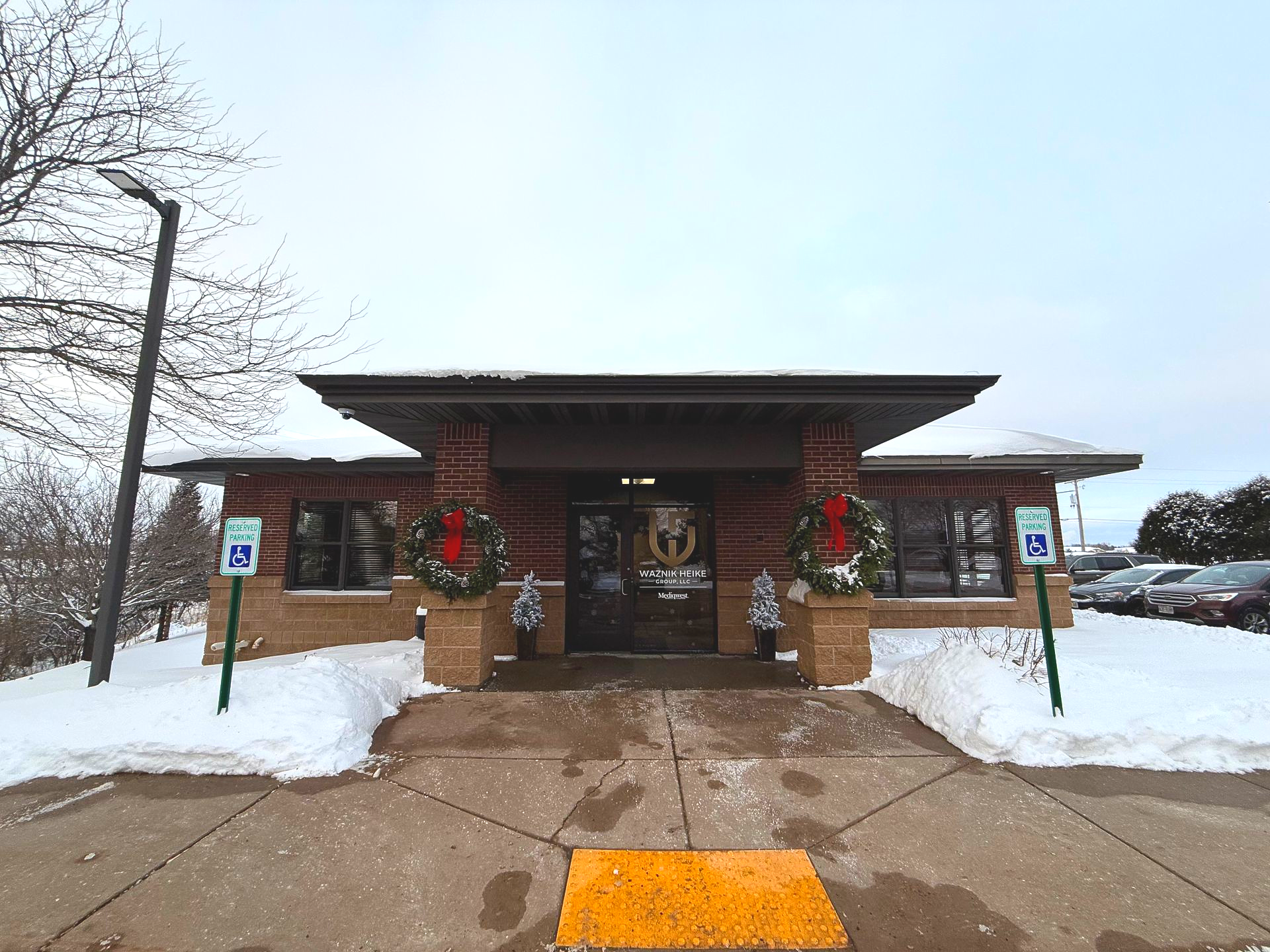 Brick building with cars parked in front, sunny day.