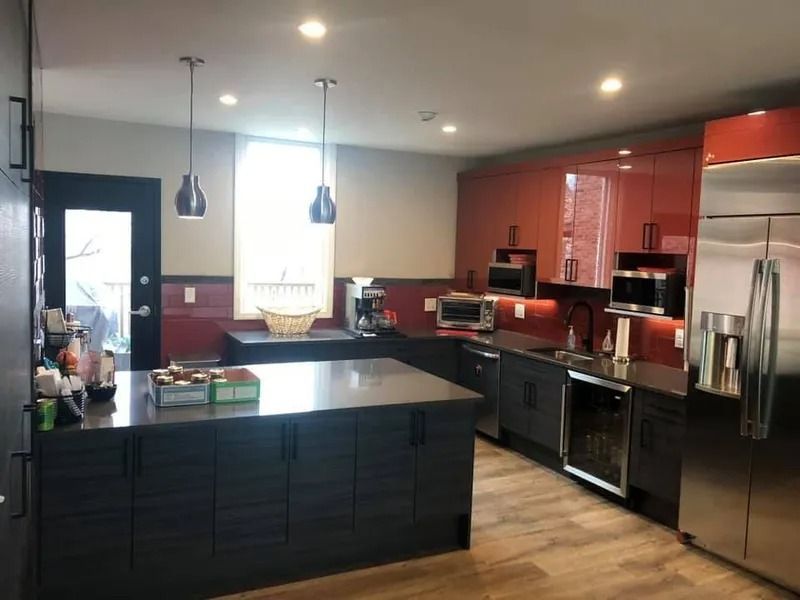 Modern kitchen with an island, cabinets, and appliances in shades of red, gray, and stainless steel.