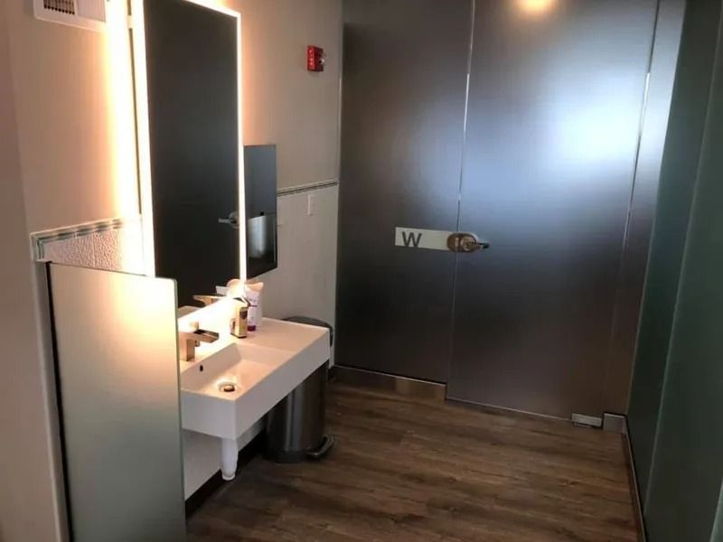 Bathroom with a white sink, mirror, and a silver door labeled 