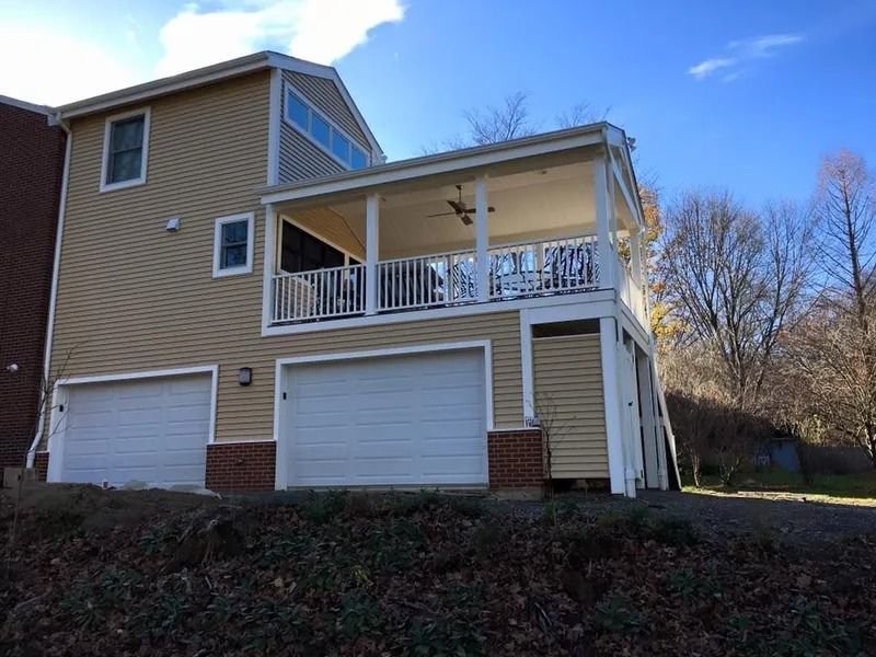 Two-story house with a beige exterior, white garage doors, and a covered porch.