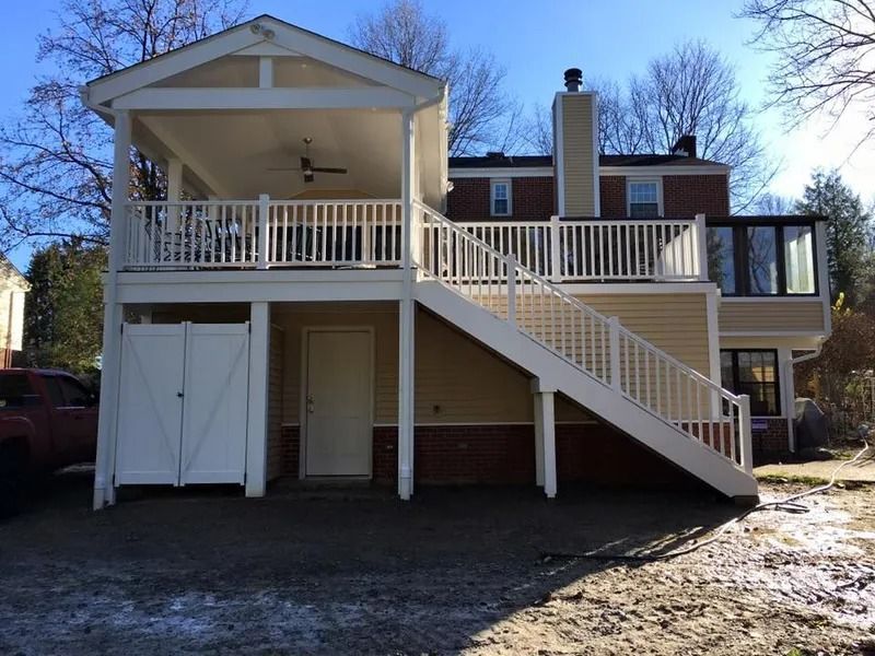 Two-story deck attached to a house with white railings, stairs, and a covered porch.