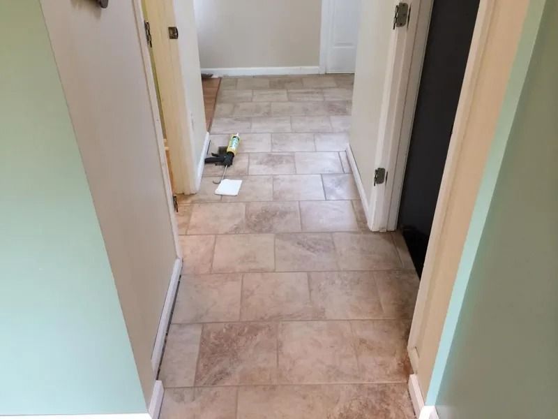 Hallway with beige tiled floor, two doorways, and green and cream walls.