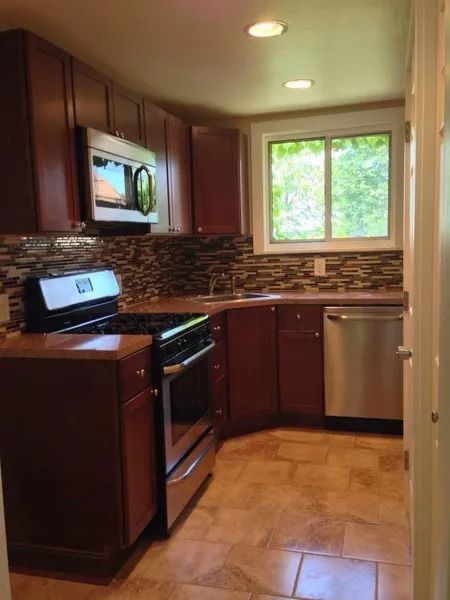Kitchen with dark brown cabinets, stainless steel appliances, and tiled backsplash.