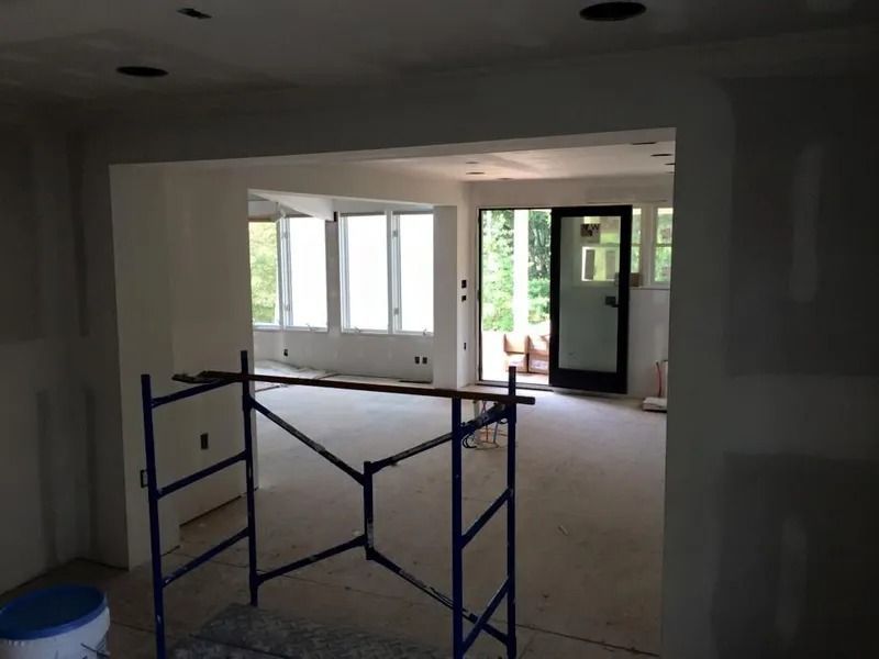 Interior under construction: Scaffolding in doorway, opening to sunroom with windows and door.