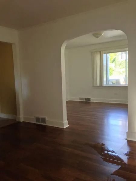 Interior view: doorway to a room with window, hardwood floors. White walls and trim, wood floors.