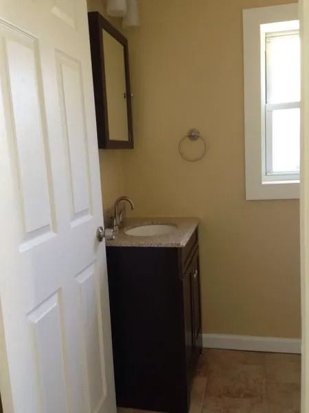 Small bathroom with dark vanity, beige walls, and a small window.