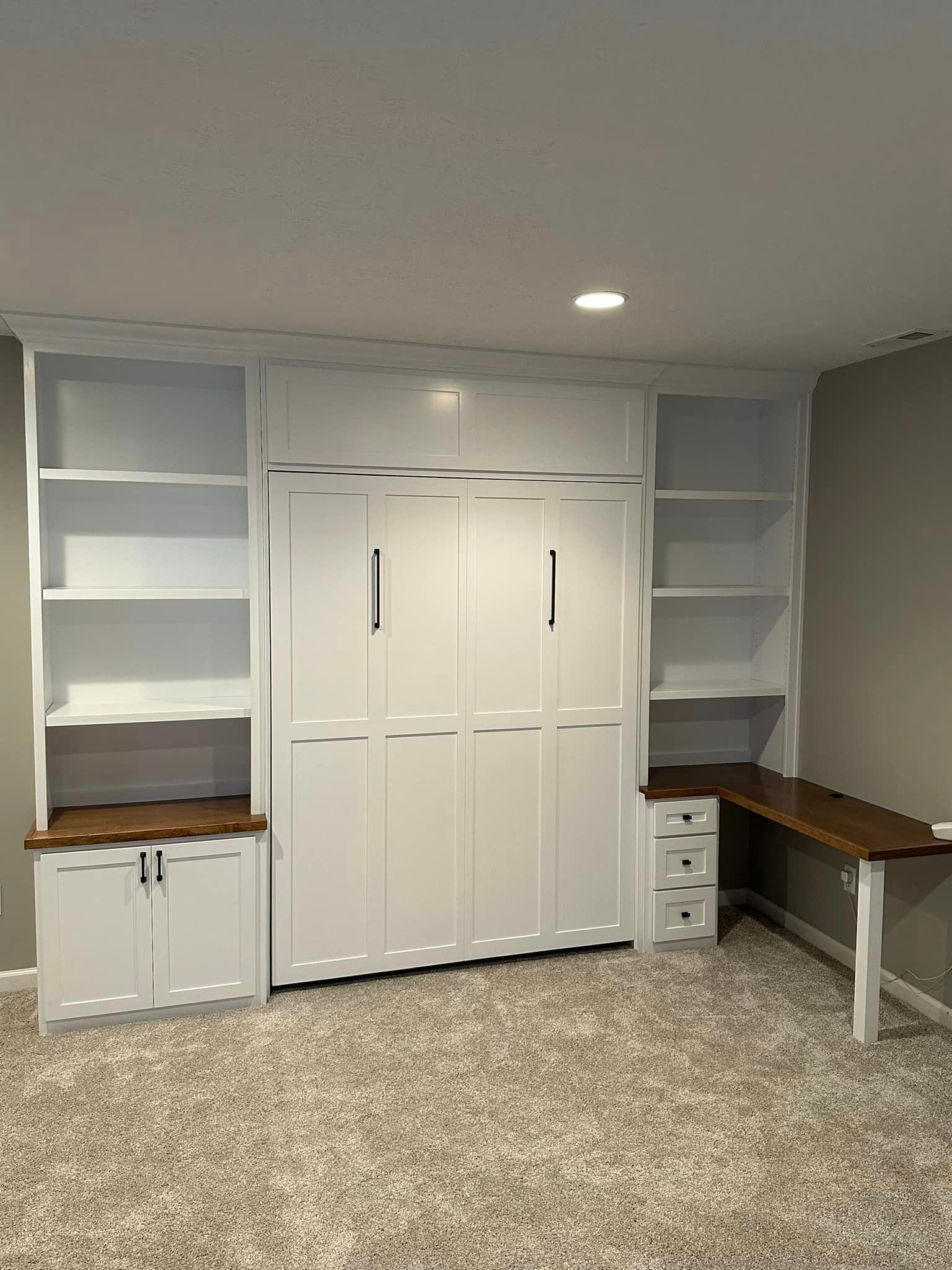 A room with white cabinets , shelves , and a desk.