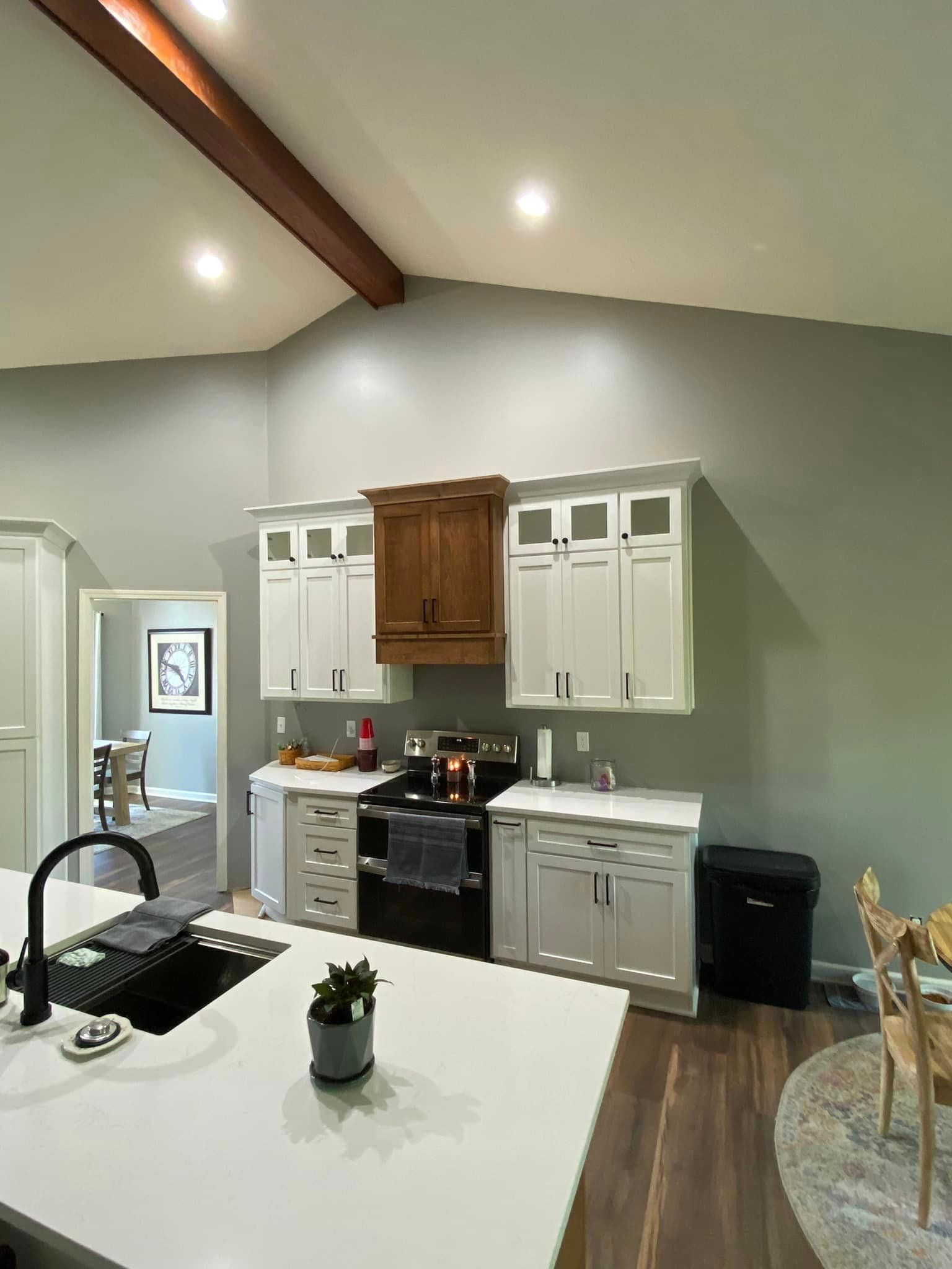 A kitchen with white cabinets , a stove and a sink