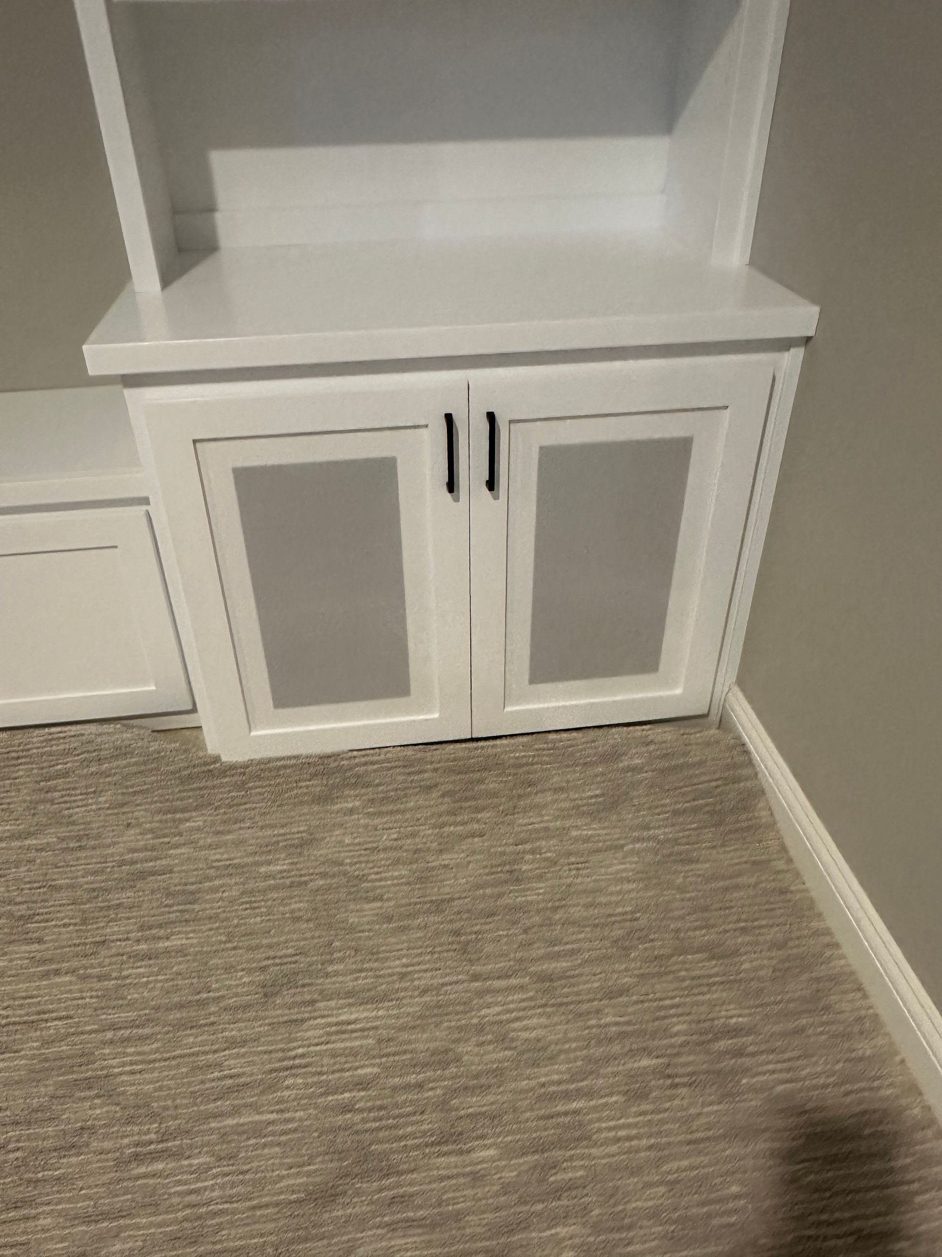 A white cabinet in a room with a carpeted floor
