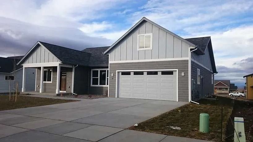 Gray house with a two-car garage under a cloudy blue sky.