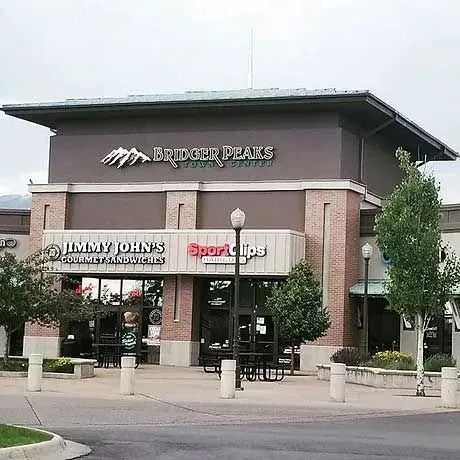 Exterior view of a shopping center with the stores: Bridgeview Dental, Jimmy John's, and Sport Clips. Gray sky.