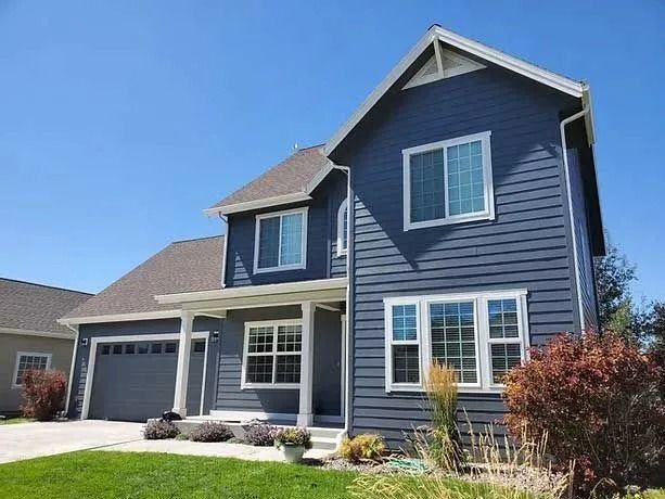 Blue house with white trim, green lawn, clear blue sky.