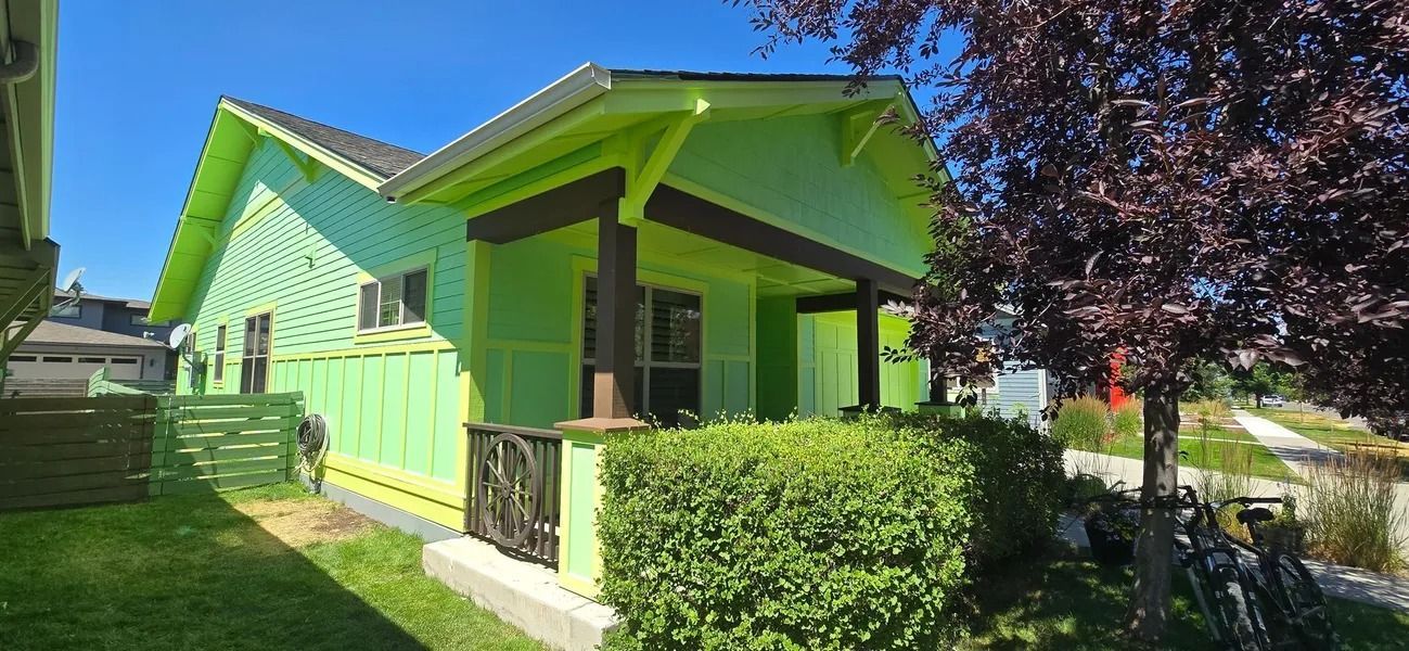 A house with green siding and dark brown trim under a clear blue sky.