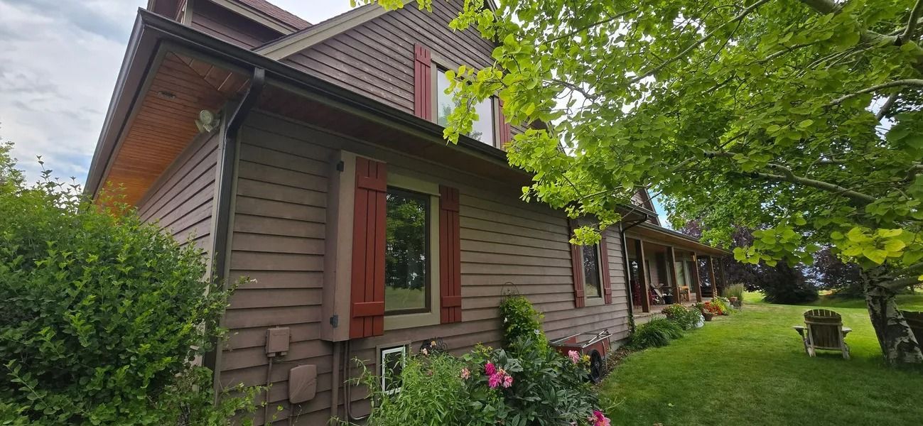 Brown house with red shutters and lush green lawn.