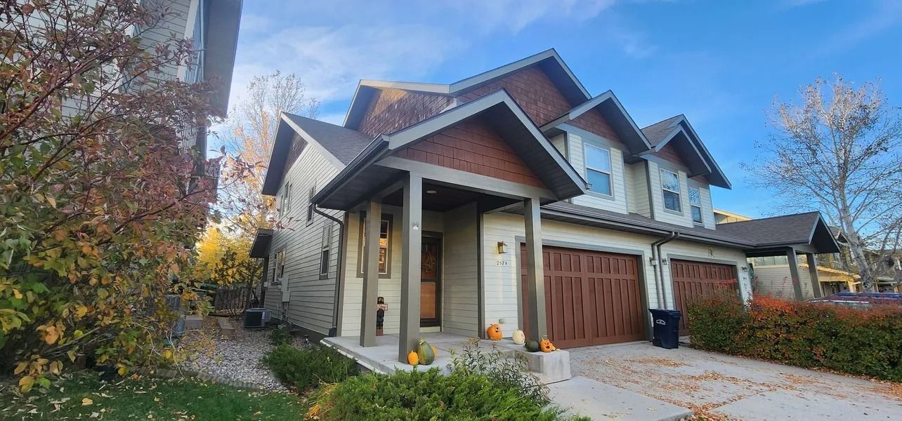 Townhouses with brown garage doors and accents, fall foliage, sunny day.