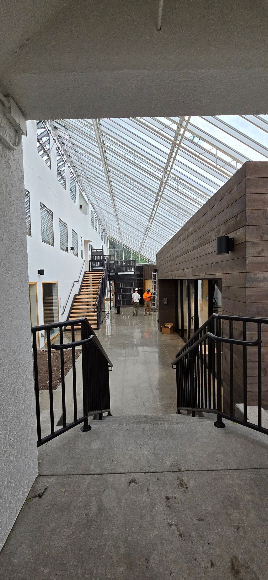 Hallway with glass roof, white walls, and wooden accents. Stairs lead to the upper level.