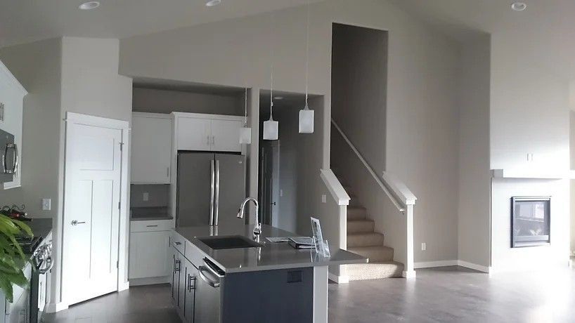 Open-concept kitchen with island, stainless steel appliances, stairs to upper level, and fireplace.