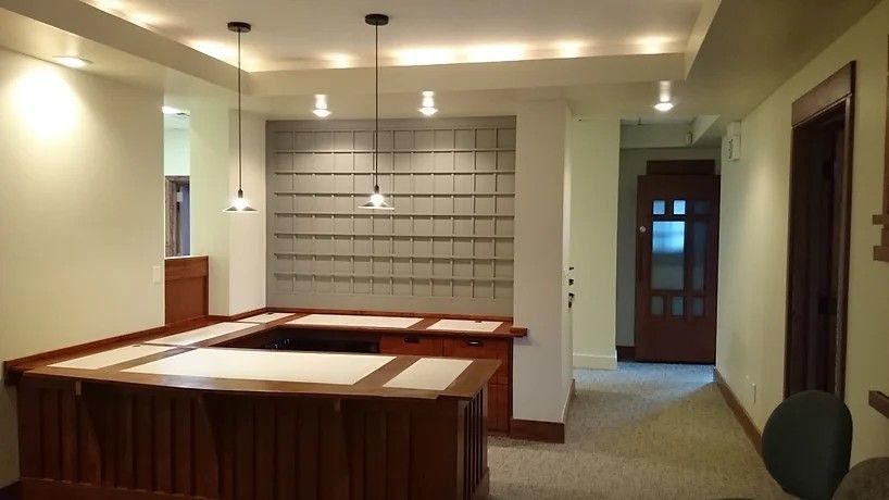 Office lobby with mailboxes, wooden desk, and pendant lights.