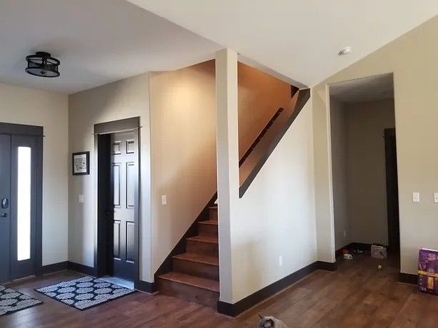 Interior view: Entryway with stairs, dark trim, and wood flooring.