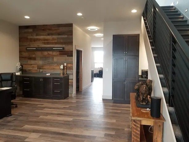Modern office interior with wood accent wall, cabinetry, and staircase.