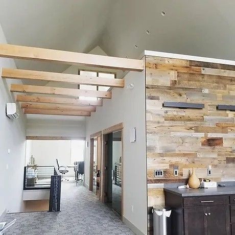 Interior view of a modern hallway with exposed wooden beams, a wood-paneled wall, and glass doors.