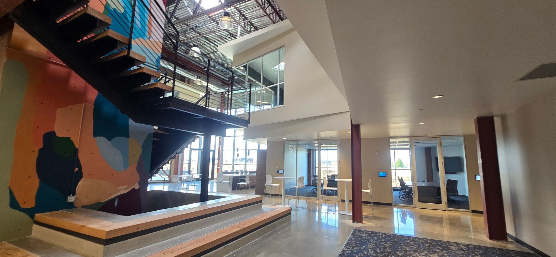 Modern interior with staircase, mural, and office spaces.