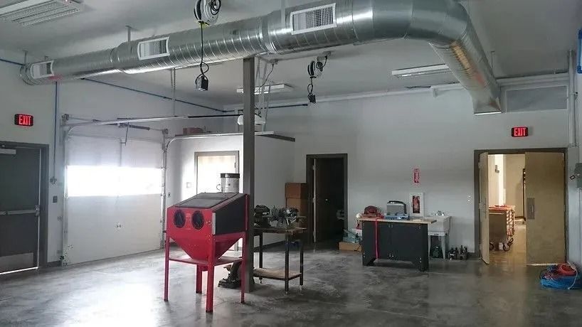 A workshop interior with a blast cabinet, air ducts, and various tools.