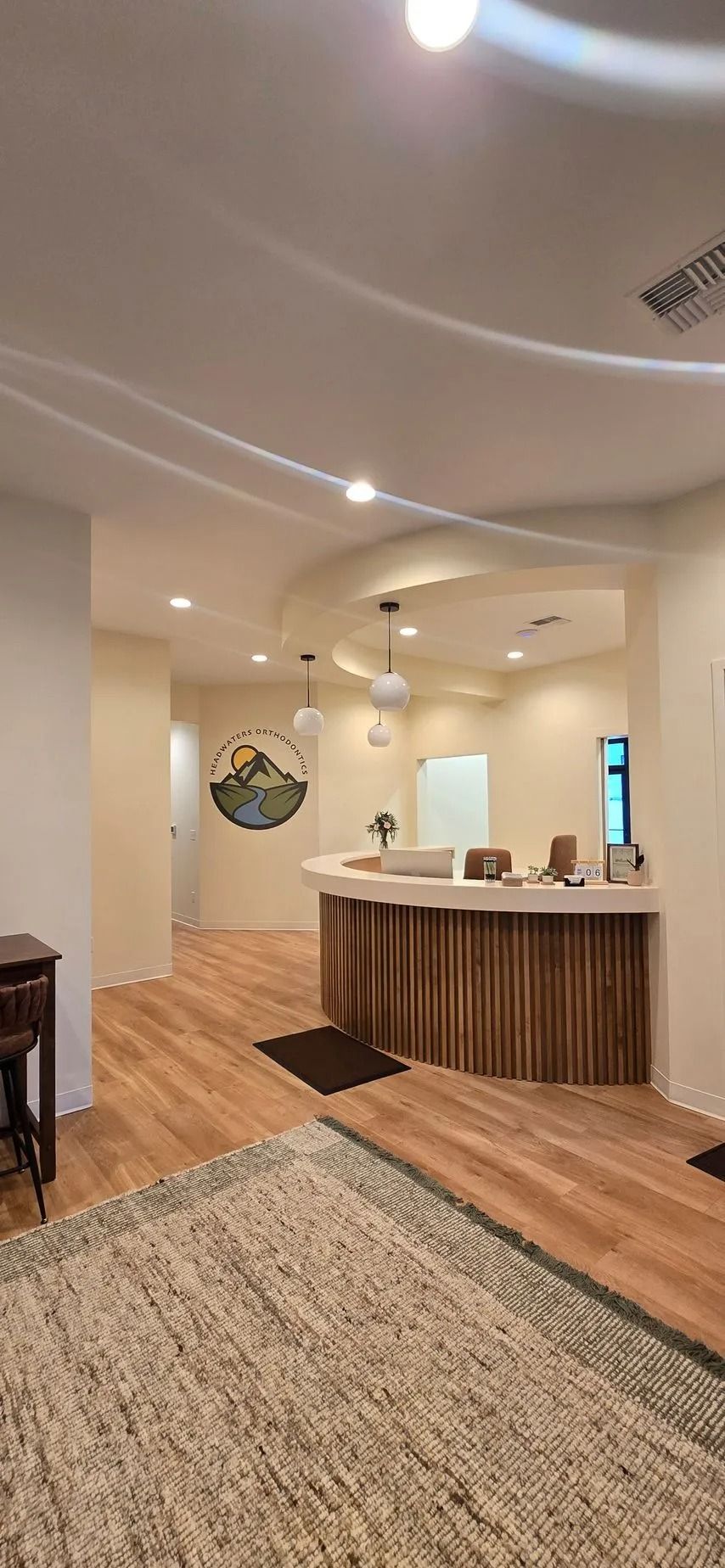Interior view of a modern reception area with wooden floor and a curved reception desk.