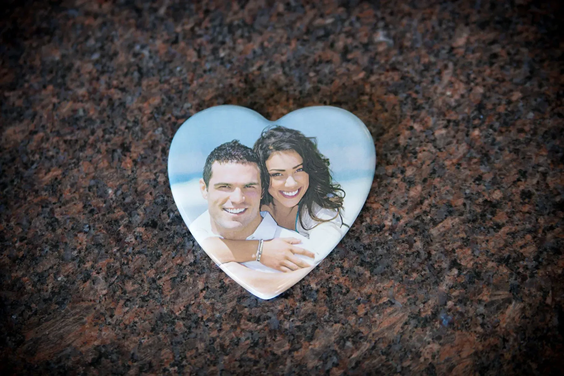 Heart-shaped photo of a smiling couple on a dark stone surface