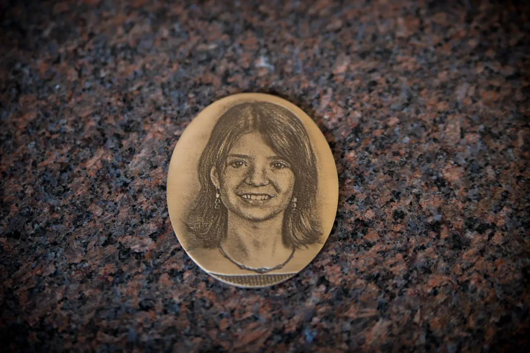 Round coin with a smiling engraved portrait on a speckled stone surface