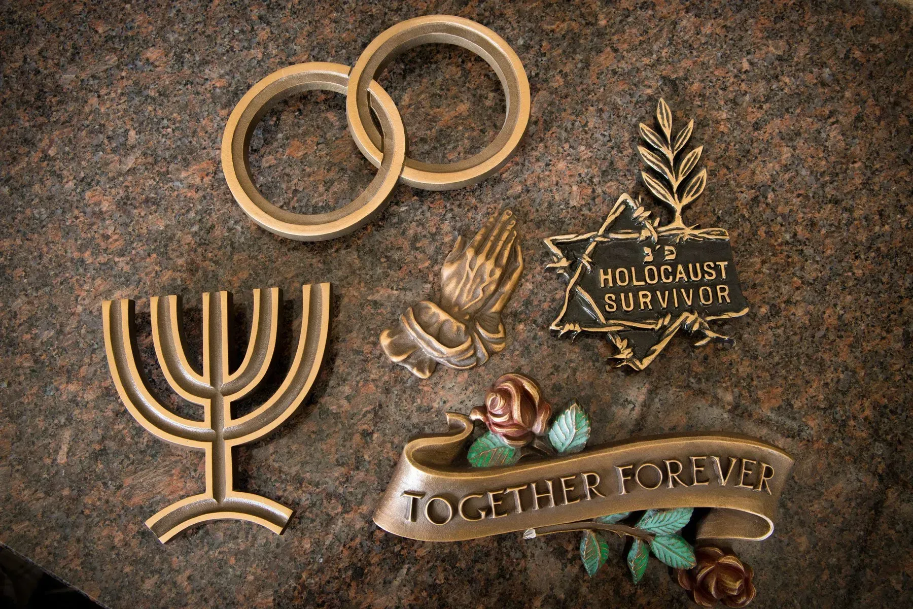 Bronze Holocaust memorial with rings, menorah, olive branch, and banner reading “Together Forever”