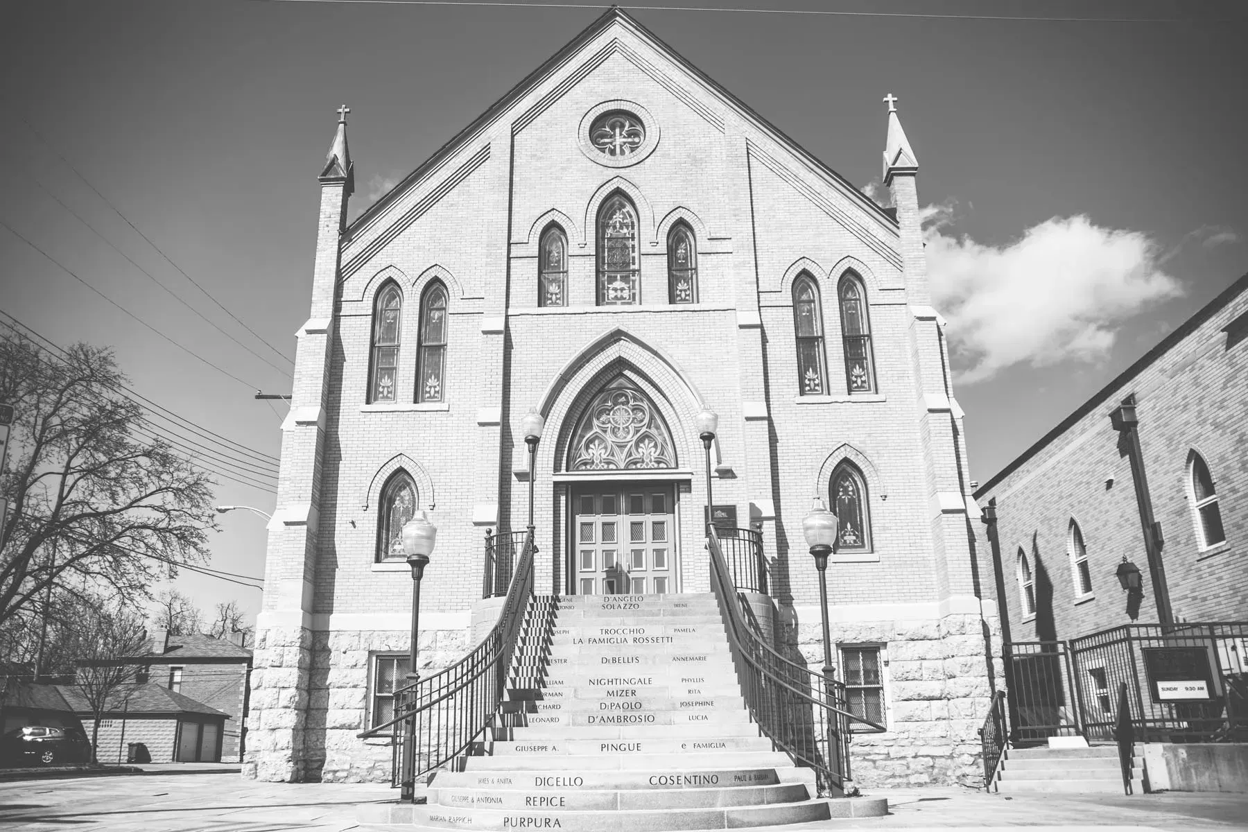 Black-and-white photo of a church facade with steps and a central arched entrance in winter snow.