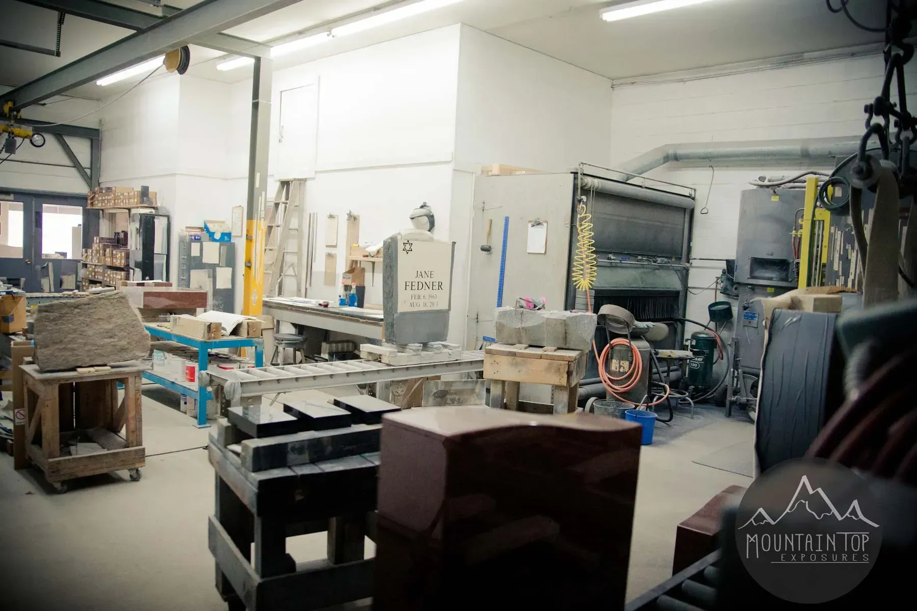 Industrial workshop with machinery, worktables, and equipment under bright overhead lights