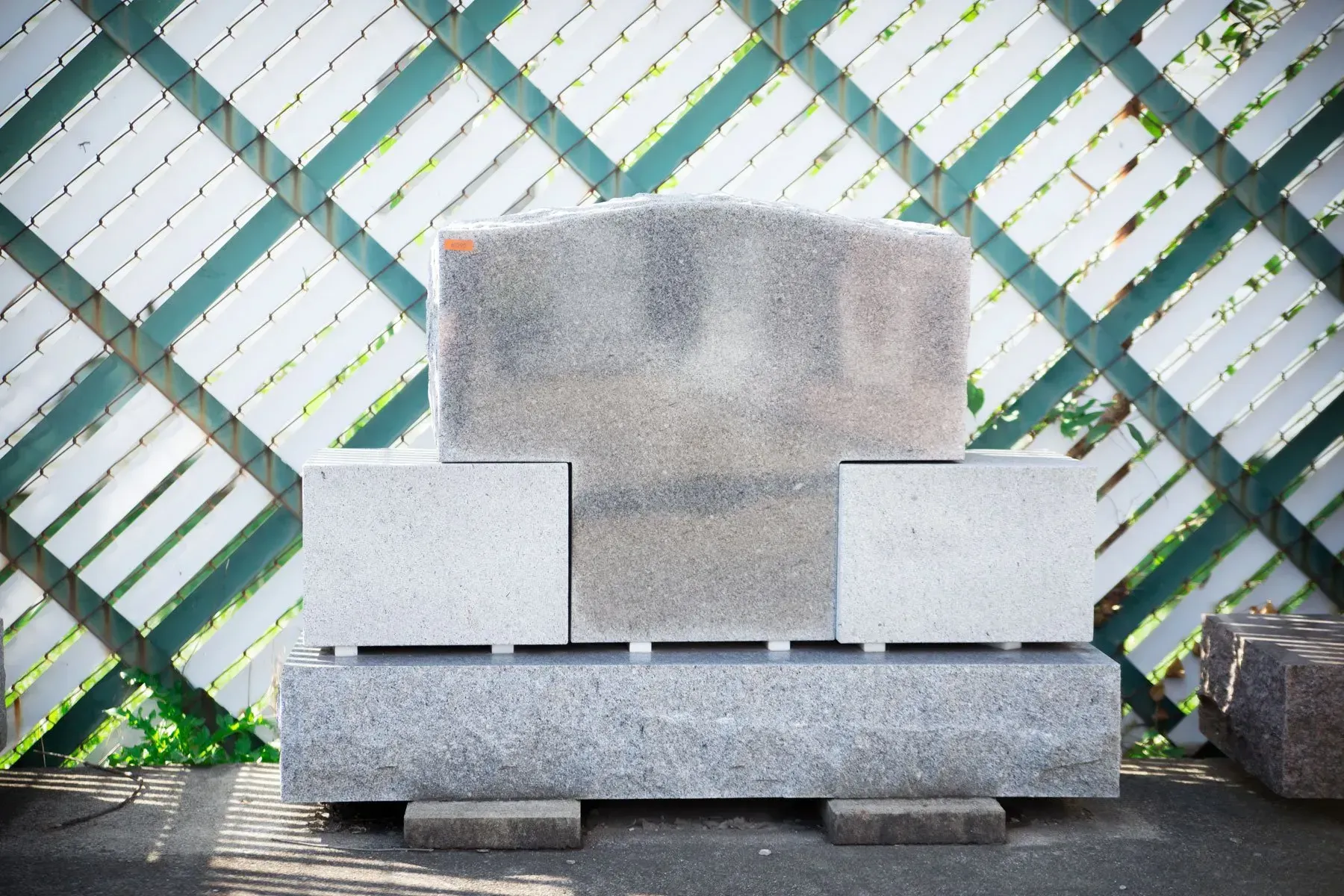 Stacked concrete blocks in front of a green lattice fence outdoors