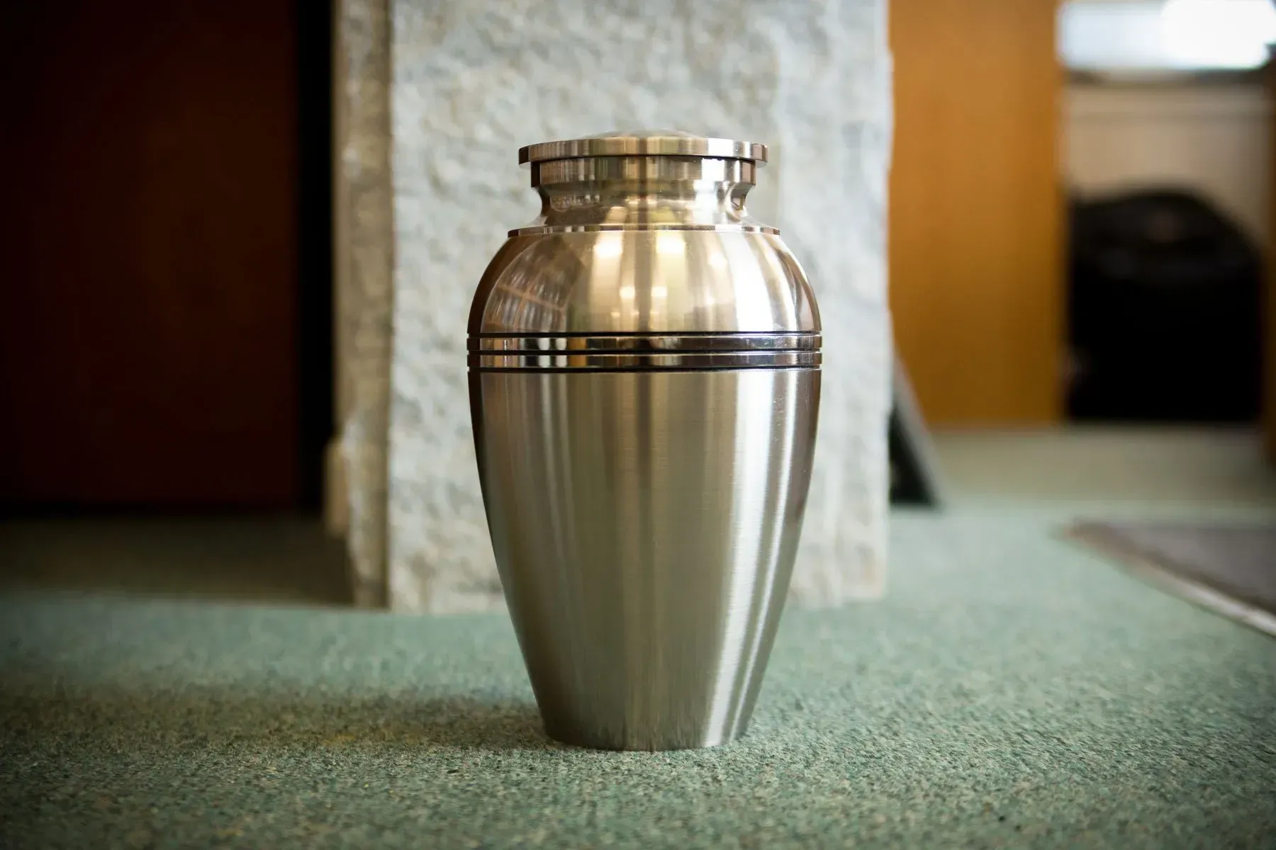 Silver funeral urn on a green carpet in a memorial room
