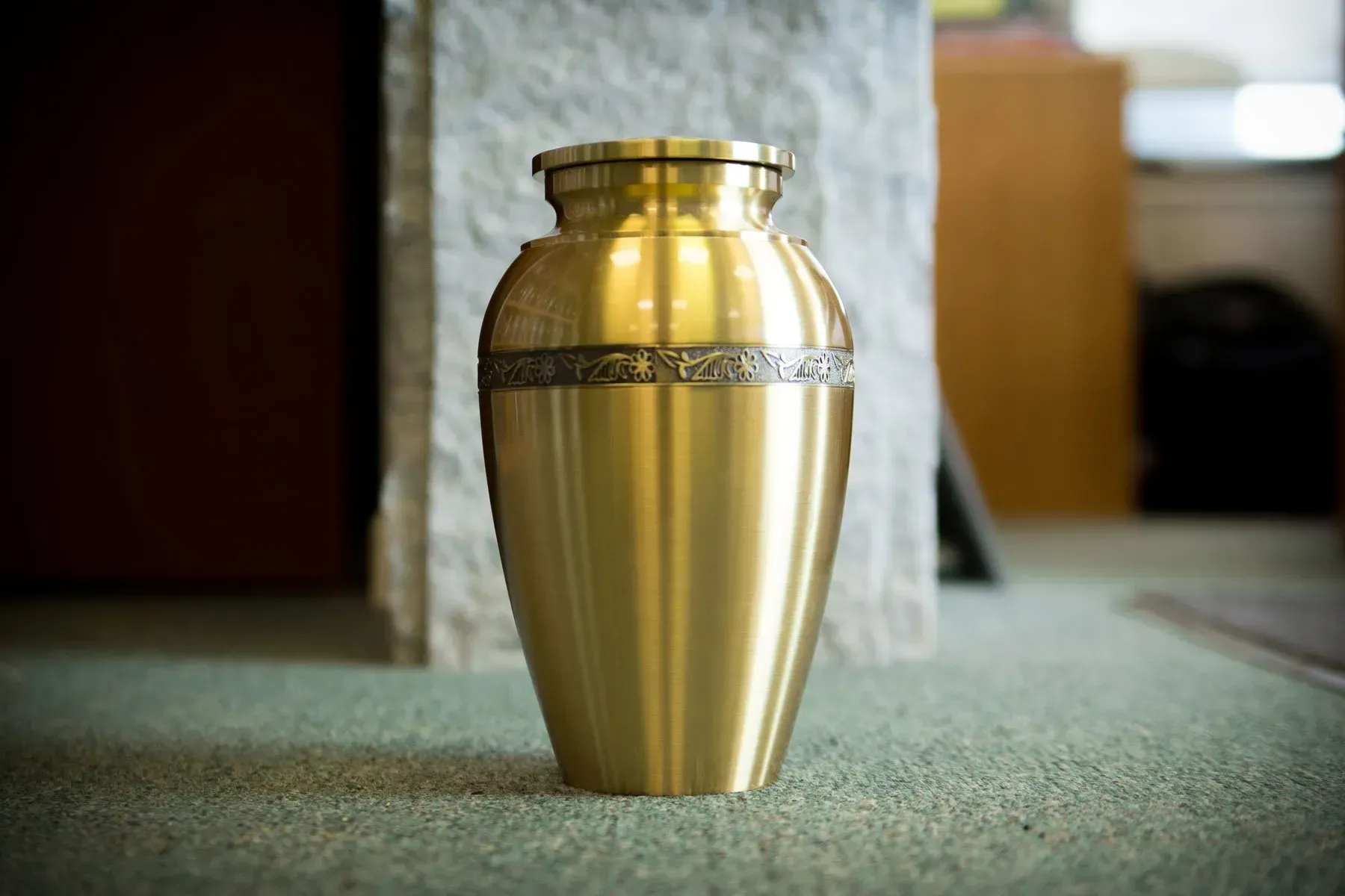 Gold funeral urn on a carpeted floor
