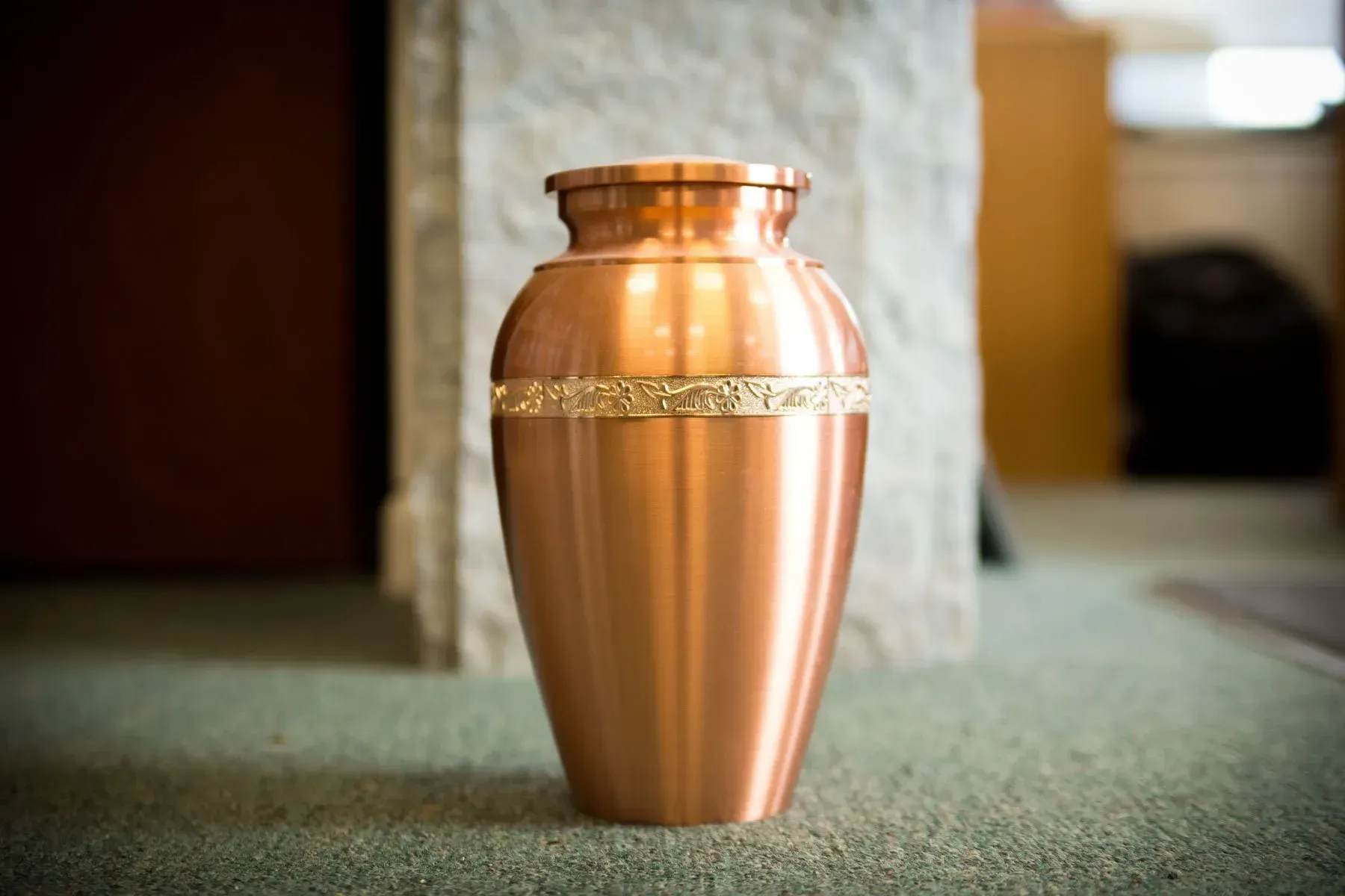 Copper funeral urn on a carpeted floor indoors