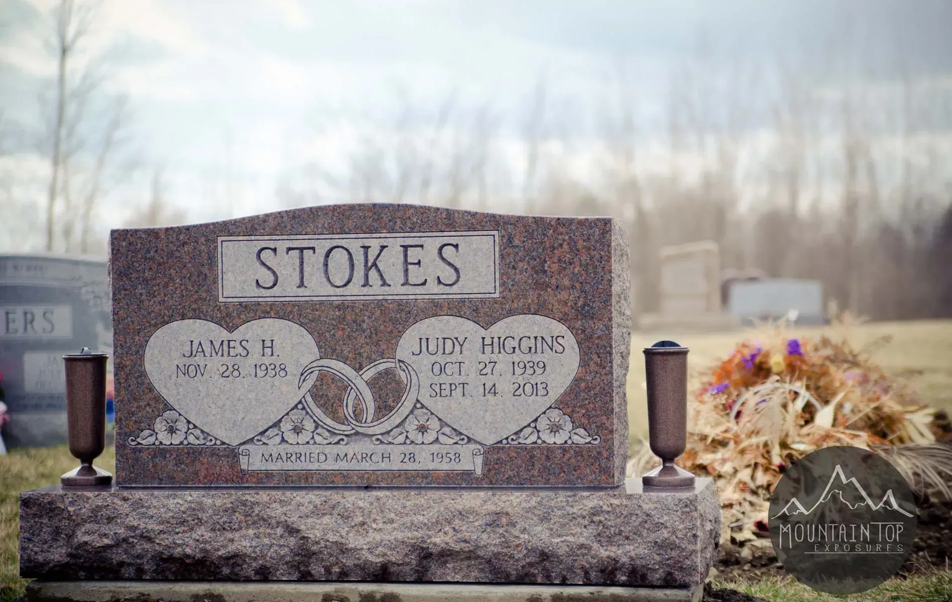 Gray Stokes family gravestone in a cemetery with flowers and a small plaque nearby