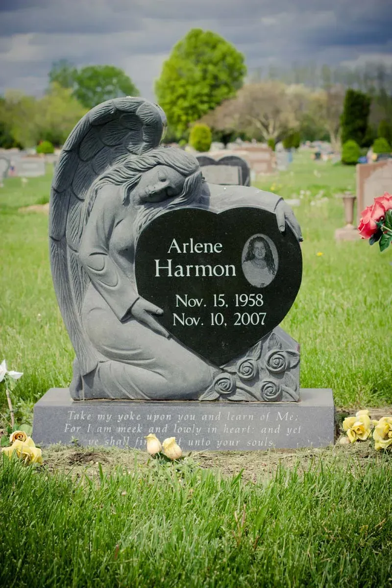 Gravestone in a cemetery with engraved portrait plaque and flowers at the base